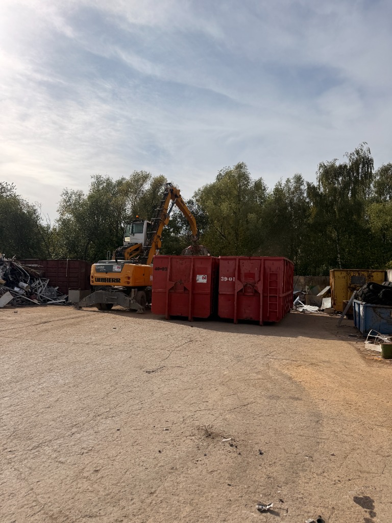Liebherr-Bagger und rote Container auf dem Recyclinghof