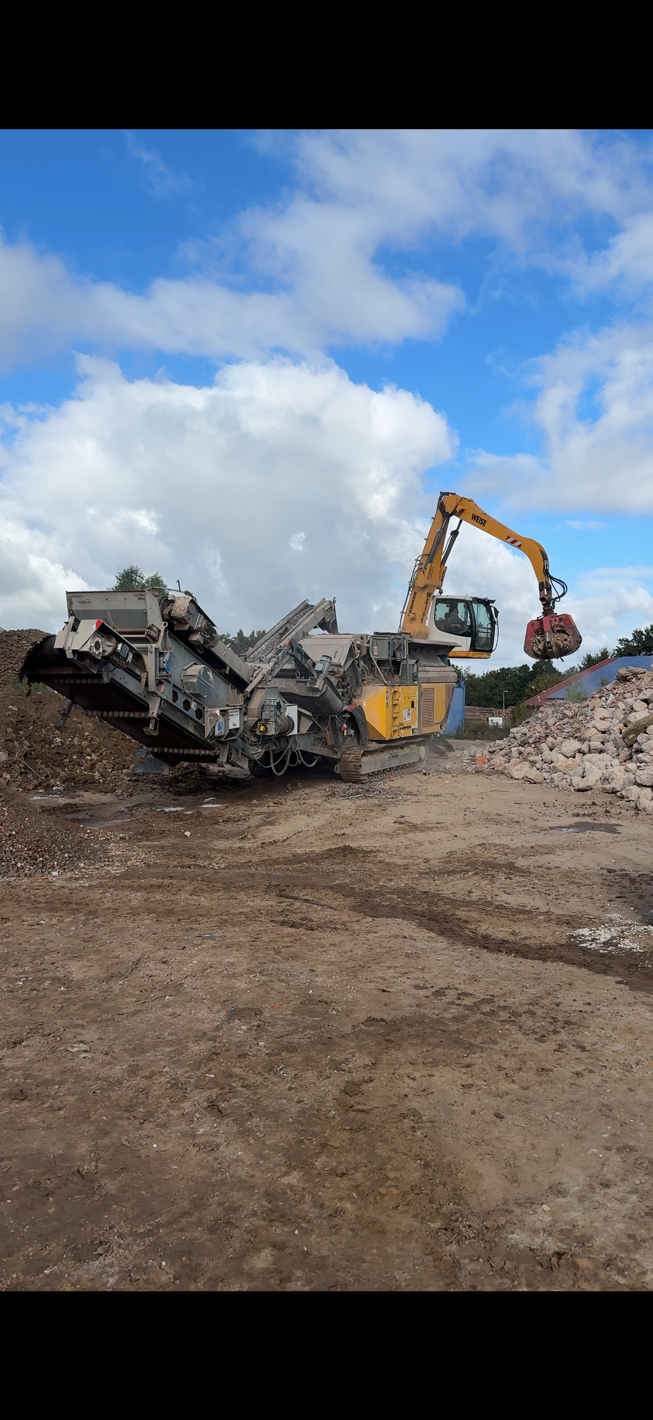 Bauschuttaufbereitung mit Brecher und Bagger auf dem Recyclinghof